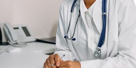 a-woman-in-white-coat-sitting-at-a-table A clinical researcher using eConsent in clinical research wearing a white coat sitting at the table.