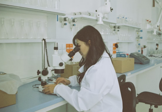 researcher-in-lab Researcher studying specimen under a microscope.
