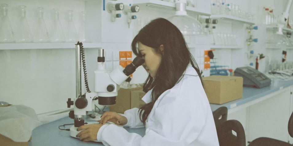 Researcher studying specimen under a microscope.