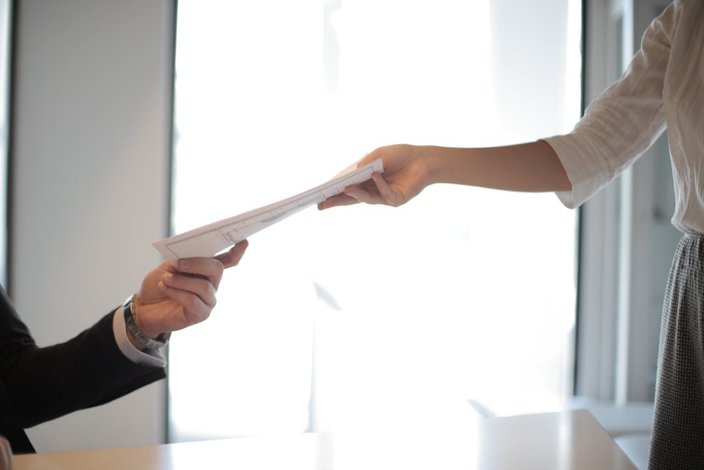 a person handing over documentation to another person.